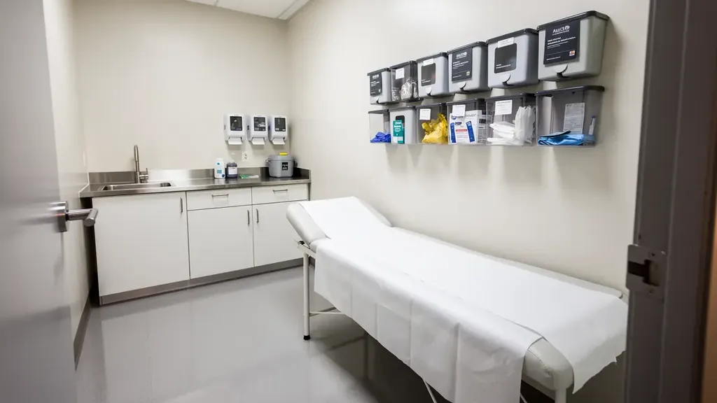 Clinic exam room with a fresh paper roll on the table and a gleaming sealed vinyl floor